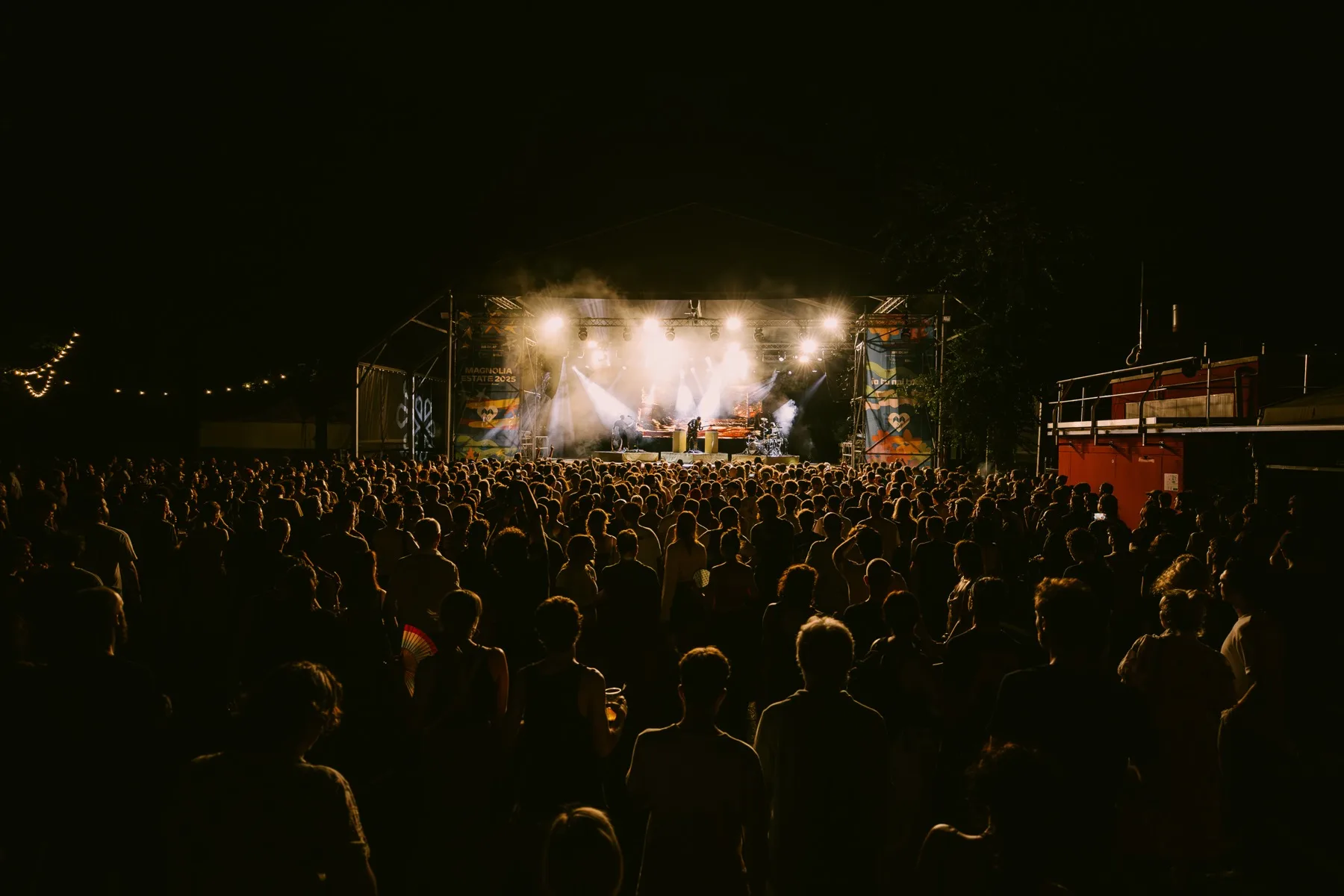 Concerto notturno al Circolo Magnolia, la folla in controluce sotto le americane