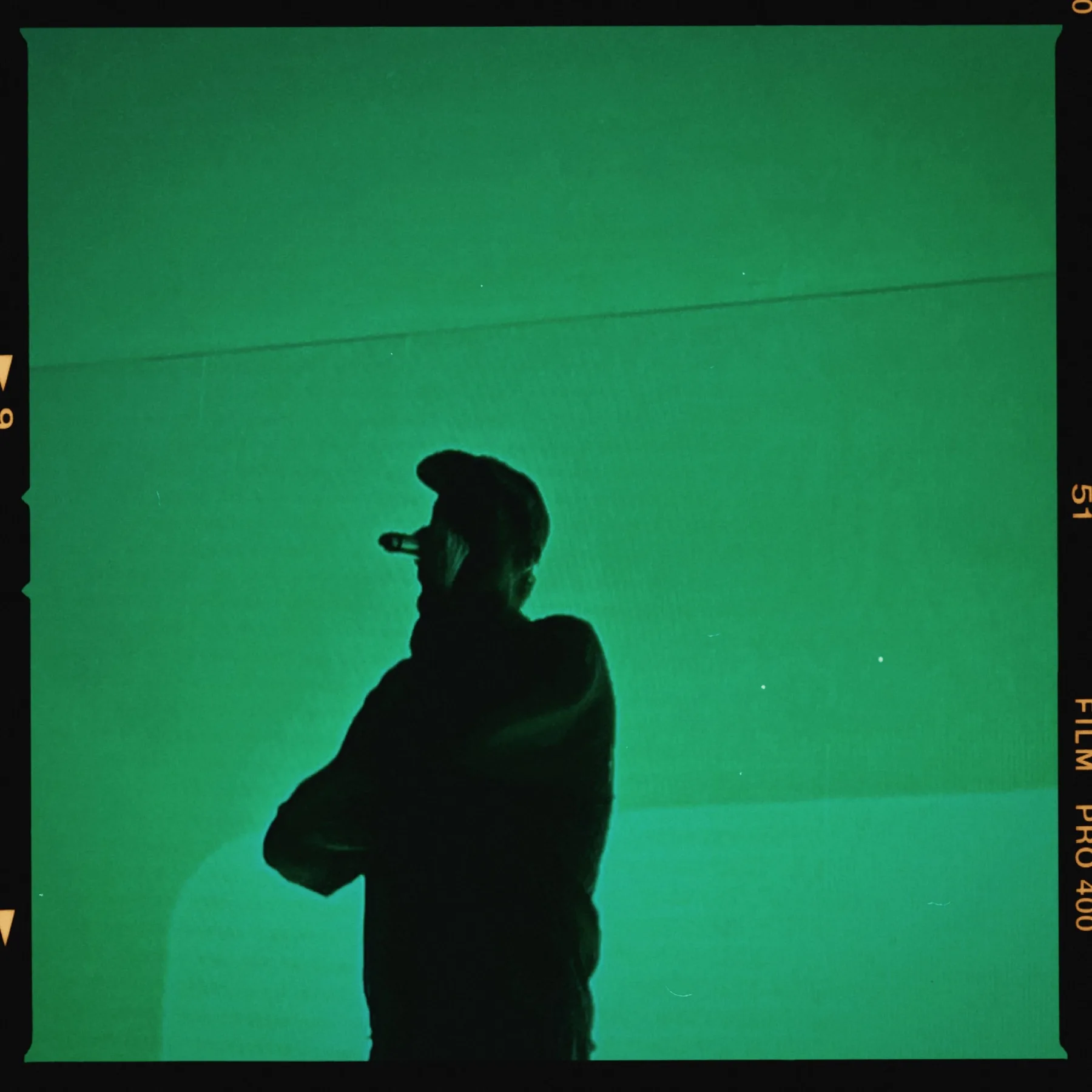 Silhouette in controluce contro uno schermo LED verde, cornice pellicola