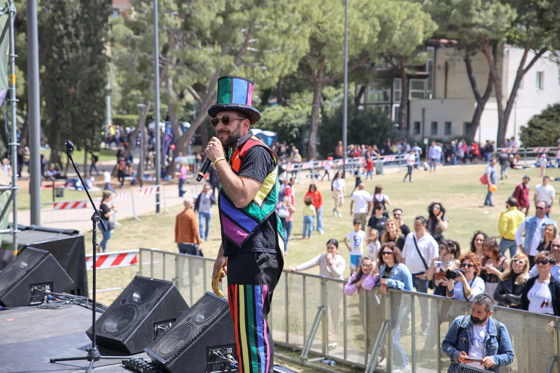 Performer in gilet arcobaleno a braccia aperte davanti al pubblico del Basket Stage